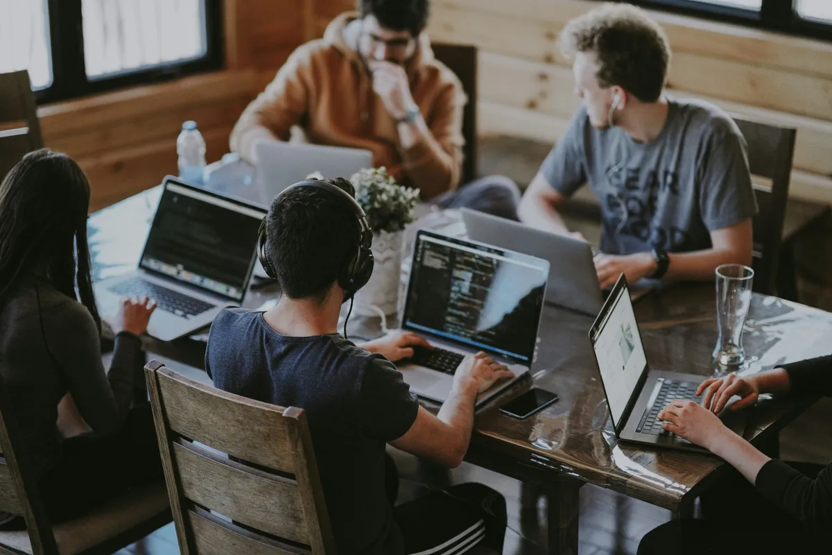 Team working together on laptops around a wooden table
