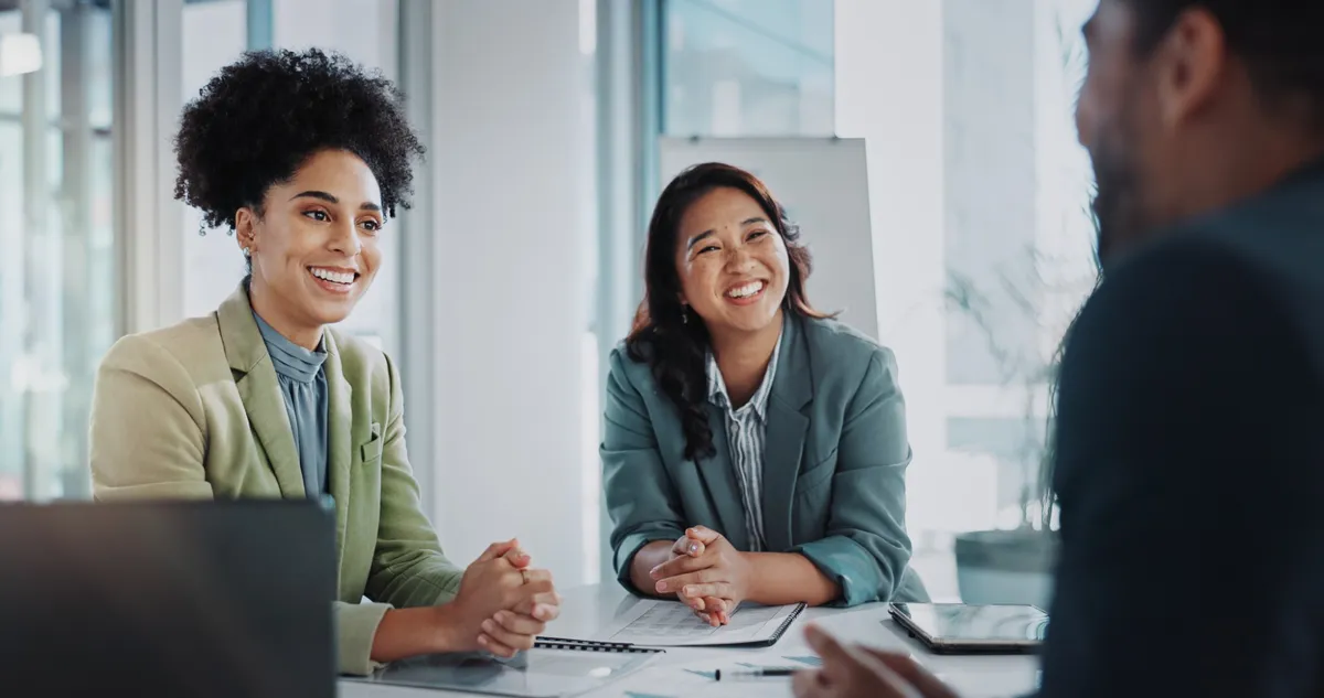 Two interviewers smiling across a meeting table during an interview